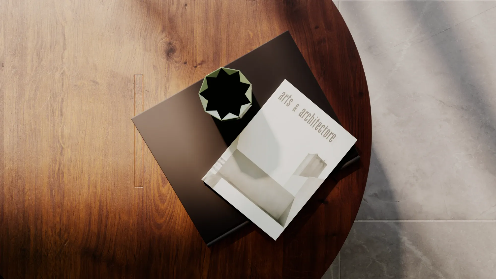 Top view of a round walnut tea table with a recessed inlay, a dark hardback, an arts & architecture magazine and a faceted green vase, on a stone floor in soft window light.